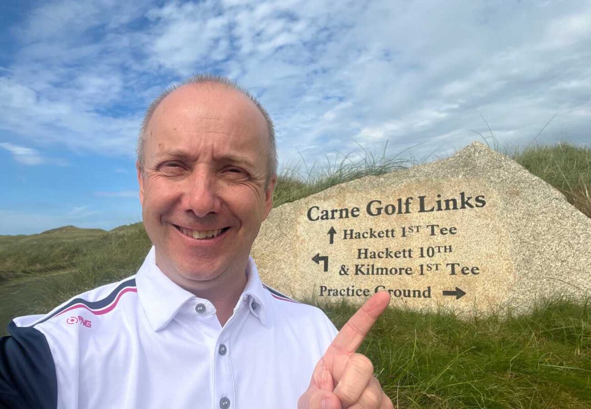 Carl Broadbent at Carne golf links stood in front of the club sign 